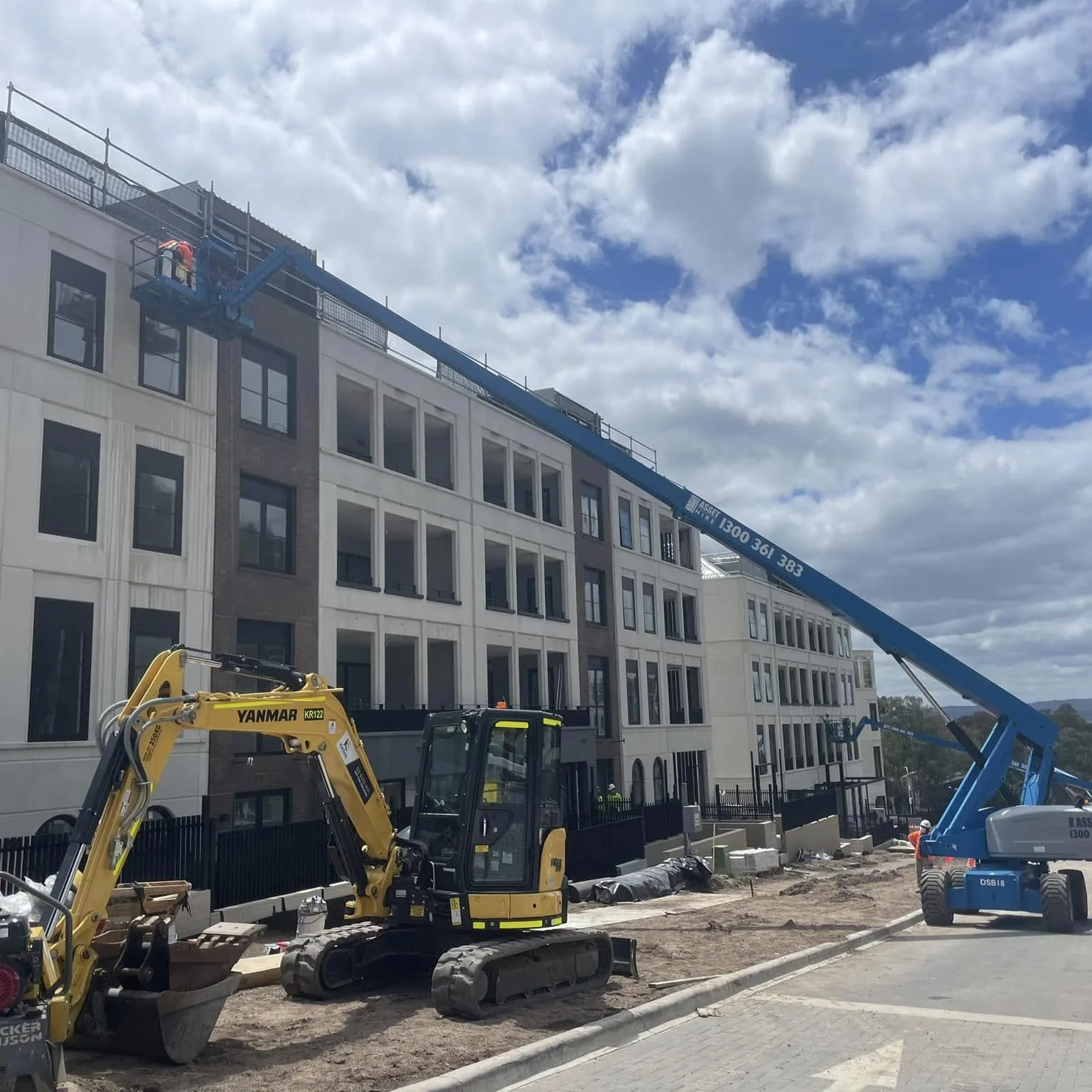 A telescopic boom lift and an excavator on an active construction site