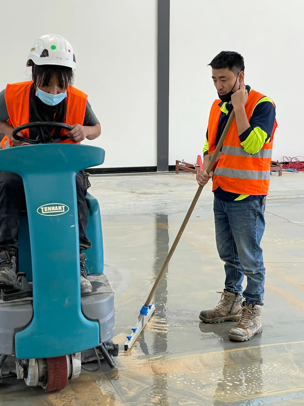 Two workers in orange hi-vis on a flooded concrete slab