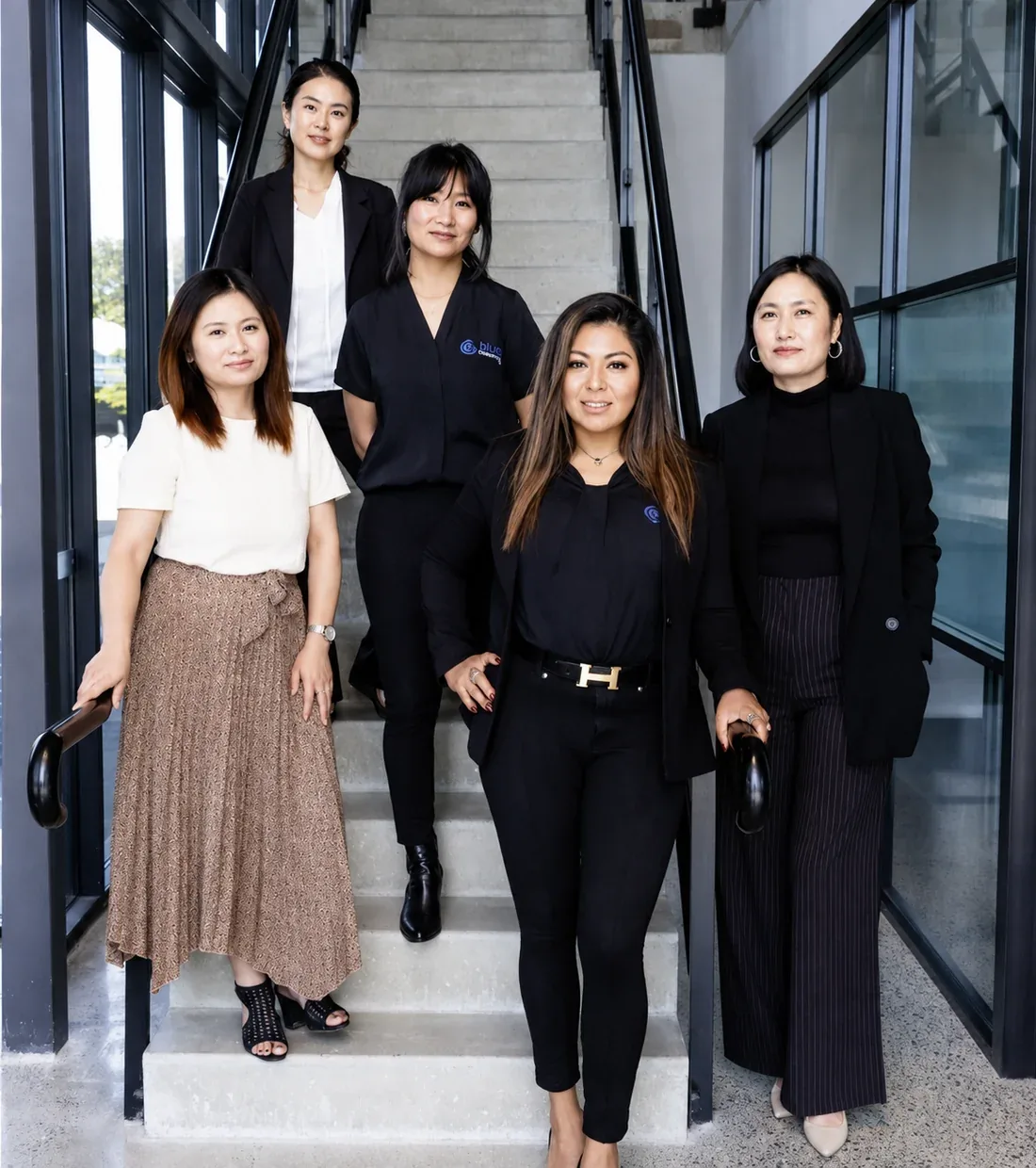 Melody Rodriguez at the front of the Blue Cleaning Group team on the stairs at our Turner office