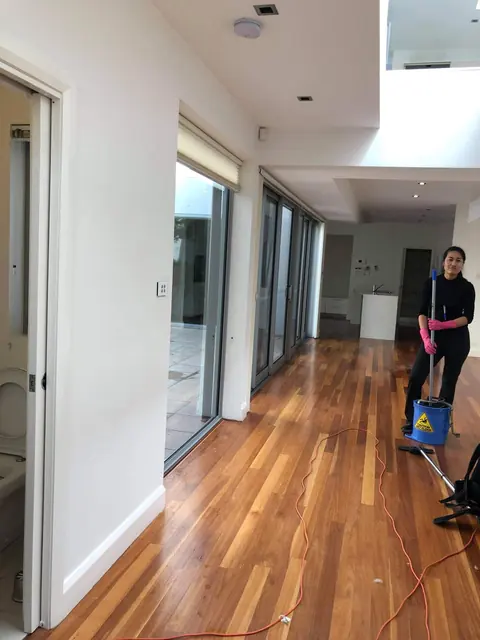 A cleaner mopping the timber floor of an emptied open-plan living area at the end of a lease