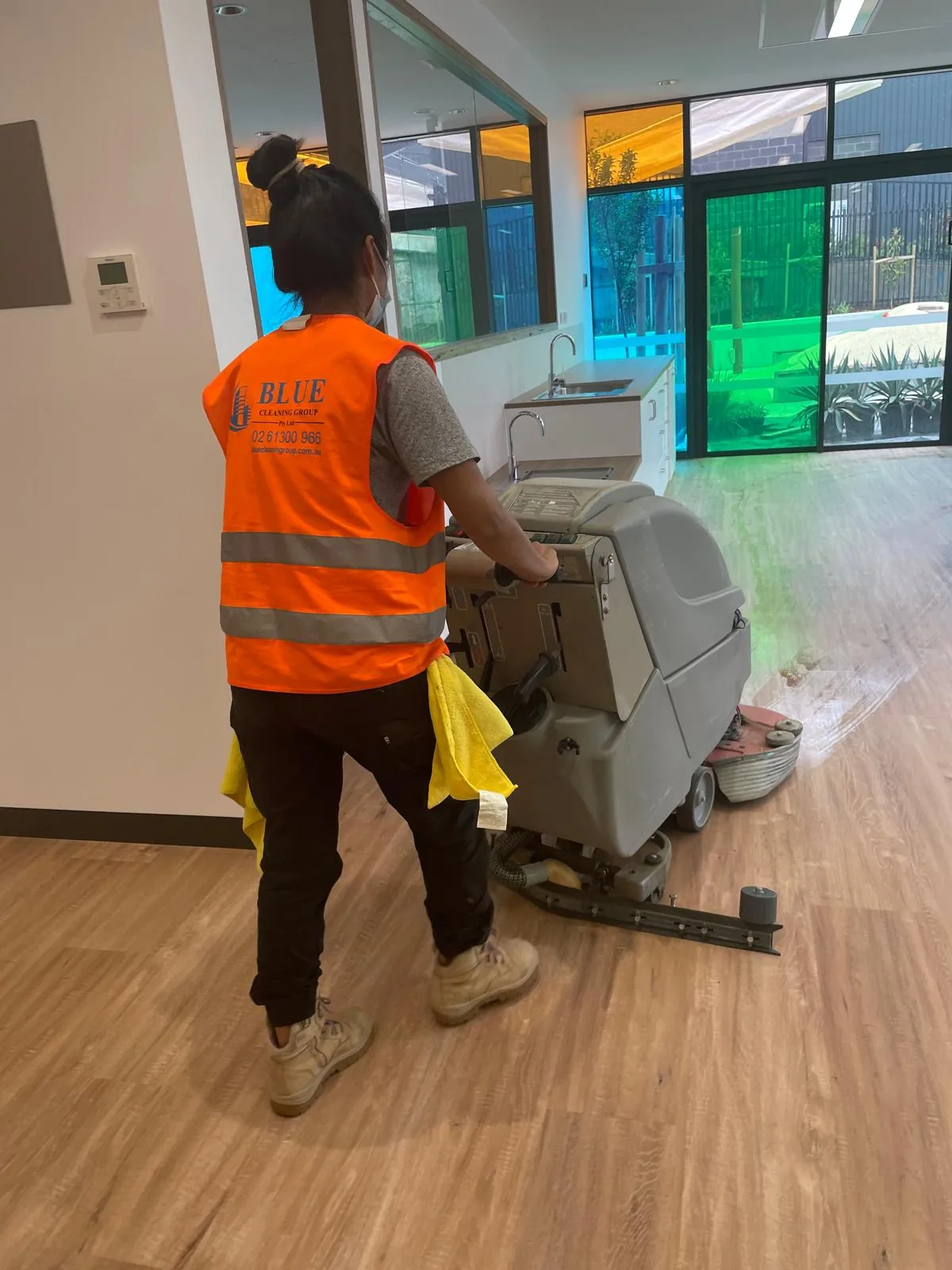 A cleaner in a Blue Cleaning Group vest pushes a walk-behind scrubber past a low bench and sink in a new childcare fit-out